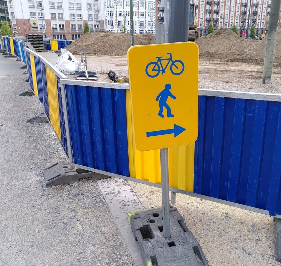 Eine Baustellenbeschilderung mit einem Pfeil nach rechts aber ein Weg ist geradeaus sichtbar.