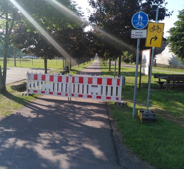Zu sehen ist eine vollständige Absperrung durch zwei Absperrelemente für Baustellen. Das Verkehrszeichen für gemeinsamer Rad- und Fußverkehr ist weiterhin sichtbar.