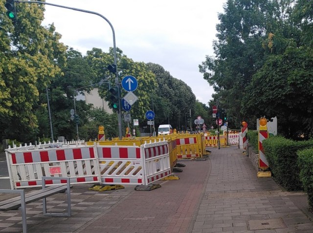 An einer Hauptstraße ist der Radweg vollständig und der Gehweg teilweise von einer Baustellenabsperrung blockiert. Dazu kommt eine verwirrenden Beschilderung.