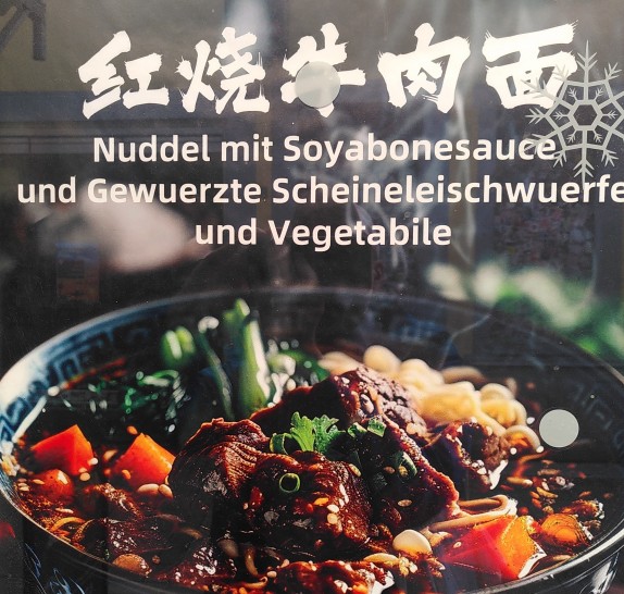Die Abbildung zeigt ein Gericht, asiatische Schriftzeichen und den Text: "Nuddel mit Soyabonesauce und Gewuerzte Scheinleischwuerfel und Vegetabile"