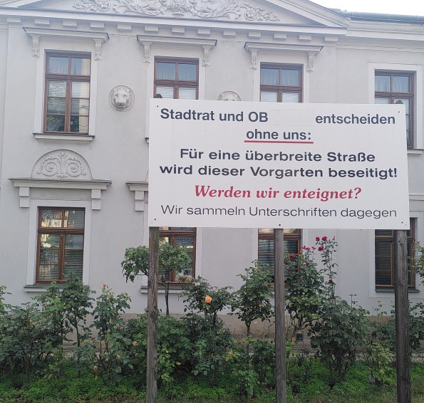 Vorgarten mit einem Schild, welches Gegenwehr der Bevölkerung gegen den Ausbau der Königsbrücker Straße zeigt