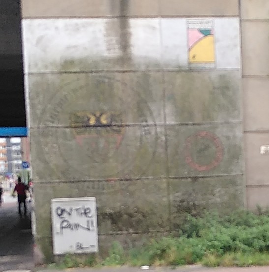 Unter einer Patina aus Moos oder Algen ist das Stadtwappen und anderes an einem Brückenpfeiler erkennbar.