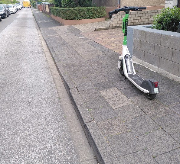Ein Ihscooter de Firma Lime Uber steht mitten auf dem Gehweg und blockiert diesen vollständig.