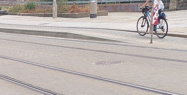 Ein Radweg wird neben der Fahrbahn von gleicher Eben auf die Ebene der Haltestelle geführt.