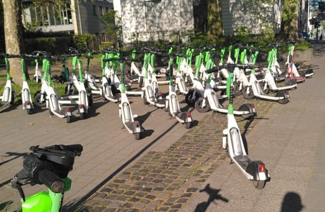 Sehr viele Ihscooter von Lime blockieren bzw. gefährden Fußverkehr in Duisburg durch dichtes Zusammenstehen.
