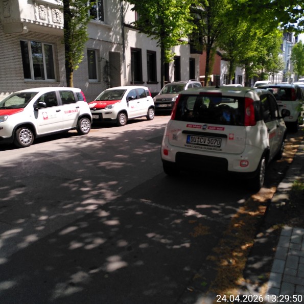 Mehrere KFZ von einem Unternehmen stehen am Straßenrand, dicht beieinander