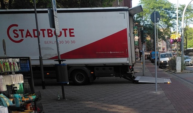 LKW mit der Aufschrift Stadtbote blockiert mit hinterem Bereich und Klappe den Gehweg vollständig den Radweg zum Großteil.