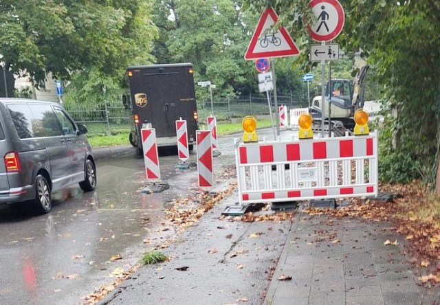 Gesperrter Gehweg mit Achtungszeichen für Radverkehr, der wohl über den nicht abgesenkten Bordstein auf die Fahrbahn wechseln soll und die Aufforderung für Fußverkehr die Seite zu wechseln.